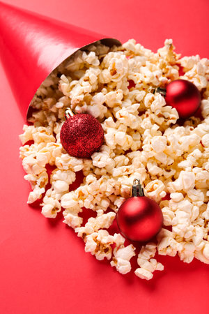 Popcorn with party hat and Christmas tree balls on red backgroundの写真素材