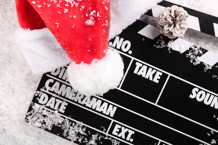 Movie clapper with Santa hat and pine cone on decorative snowの写真素材