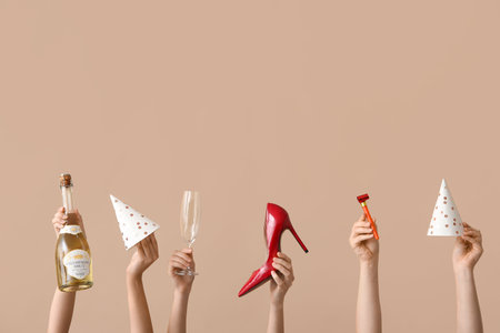 Female hands with birthday party items, bottle of champagne and stylish high heel shoe on color...