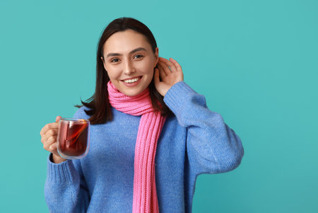 Happy young woman in scarf with glass cup of hot mulled wine on blue backgroundの写真素材