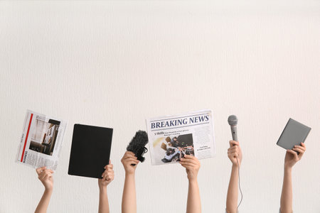 Female hands with newspapers, microphones and notebooks on light backgroundの写真素材