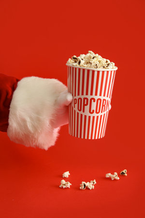 Santa Claus holding paper cup with popcorn on red background, closeupの写真素材
