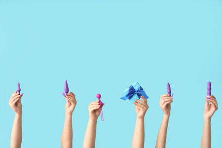Female hands with sex toys and Christmas gift on color backgroundの写真素材