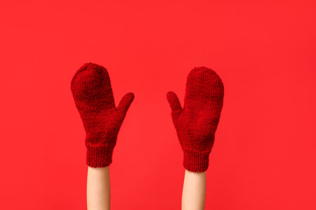 Hands in warm mittens on red backgroundの写真素材