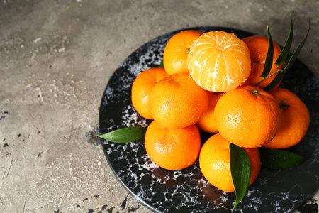 Board with sweet mandarins and leaves on gray tableの写真素材
