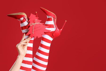 Sexy woman in Christmas stockings with decor on red backgroundの写真素材