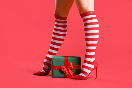 Sexy woman in Christmas stockings with gift box on red backgroundの写真素材