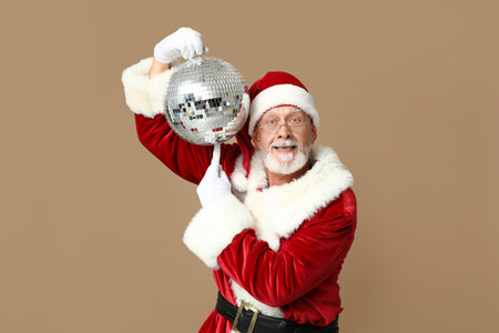 Santa Claus in glasses pointing at disco ball on brown backgroundの写真素材