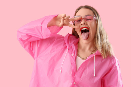 Beautiful stylish woman in raincoat posing on pink backgroundの写真素材