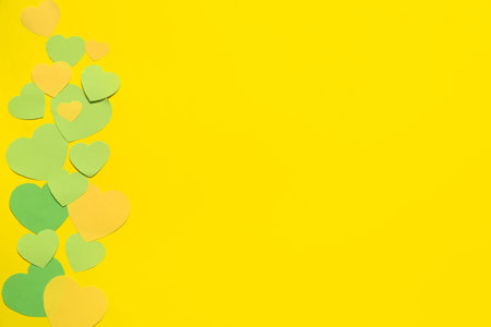 Green paper hearts on yellow background. Valentines Day celebration