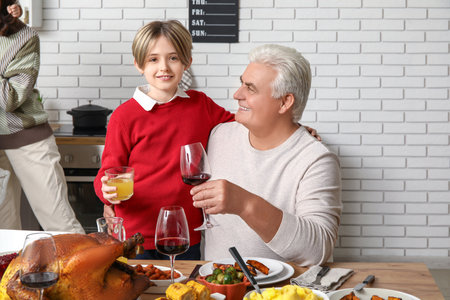 Little boy with his grandfather having dinner at festive table on Thanksgiving Dayの写真素材