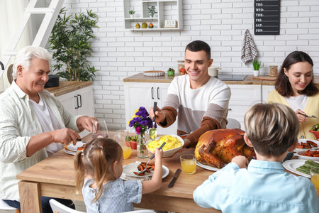 Happy family having dinner at festive table on Thanksgiving Dayの写真素材