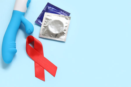 Red ribbon with vibrator and condoms on blue background. AIDS Day conceptの写真素材