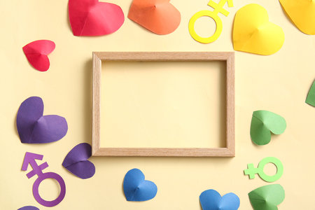 Blank photo frame, colorful paper hearts with symbols of woman and man on yellow background. LGBT conceptの写真素材