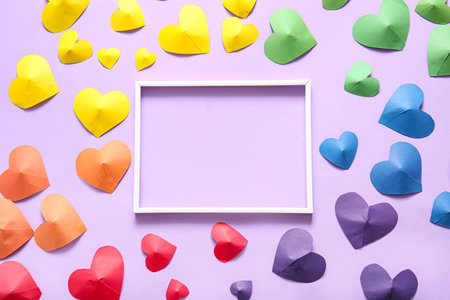 Blank photo frame and colorful paper hearts on lilac background. LGBT conceptの写真素材