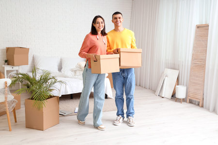 Happy young couple with boxes in bedroom on moving day