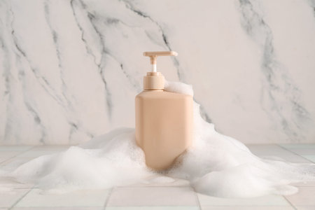 Bottle of skincare product with foam on white tile tableの写真素材