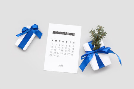 Paper calendar for December 2024 with gift boxes on gray background