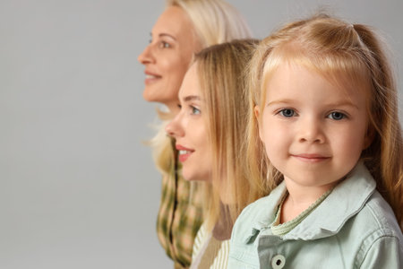 Cute little girl with her mother and granny on light background, closeup