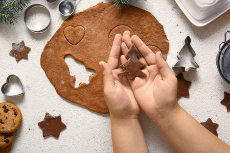 Woman with raw Christmas gingerbread cookie on grunge white background