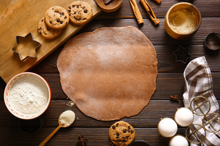 Fresh dough and ingredients for gingerbread cookies on brown wooden backgroundの写真素材