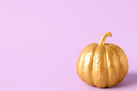 Golden painted pumpkin on lilac backgroundの写真素材