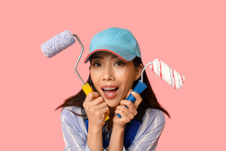 Female Asian painter with rollers on pink backgroundの写真素材