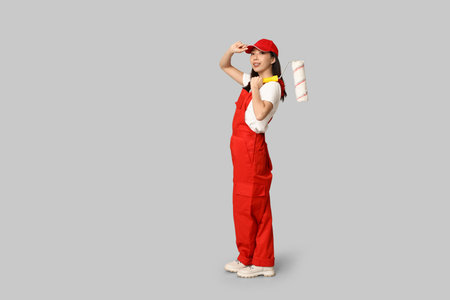 Female Asian painter with roller on gray backgroundの写真素材