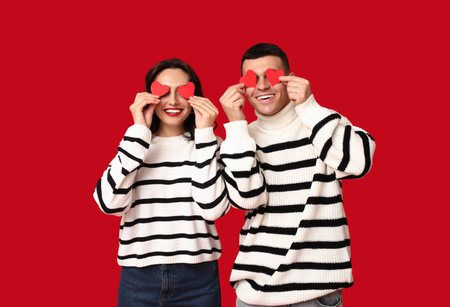 Loving young couple with paper hearts on red background. Celebration of Saint Valentine's Dayの写真素材