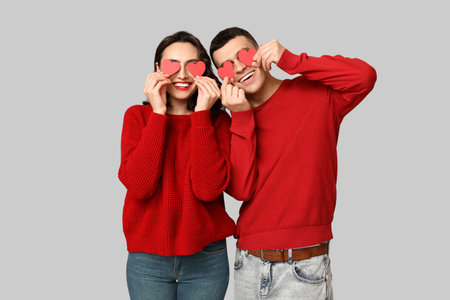 Loving young couple with paper hearts on gray background. Celebration of Saint Valentine's Dayの写真素材