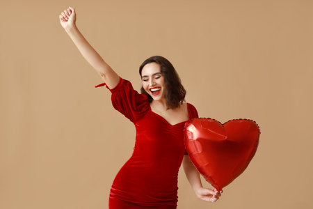 Happy young woman with heart shaped air balloon on brown backgroundの写真素材
