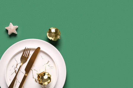 Beautiful table setting with Christmas balls and candle on green backgroundの写真素材