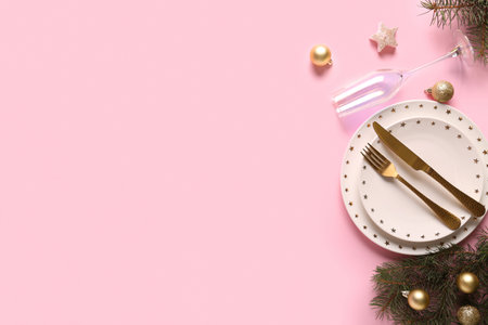 Beautiful table setting with Christmas balls and fir branches on pink backgroundの写真素材