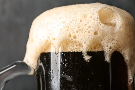 Mug of cold dark beer on black grunge background