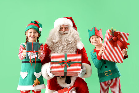 Little elves with Santa Claus and Christmas gifts on green background