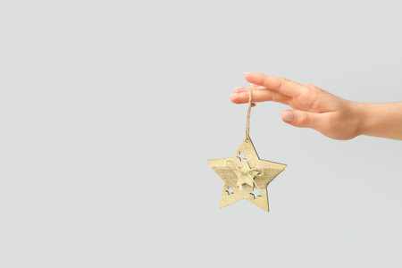 Female hand with Christmas star on gray background