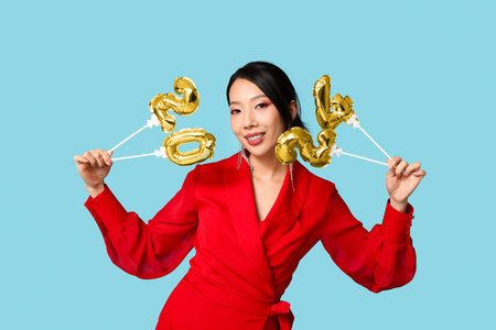 Beautiful young happy Asian woman with figure 2024 made of balloons on blue background. Chinese New Year celebrationの写真素材