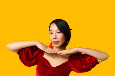 Beautiful young Asian woman on yellow background. Chinese New Year celebrationの写真素材