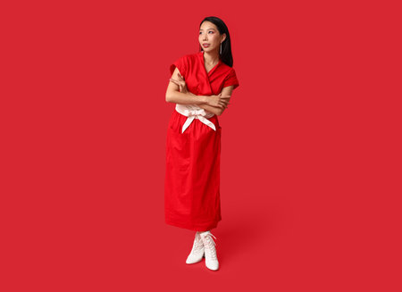 Beautiful young stylish Asian woman on red background. Chinese New Year celebrationの写真素材