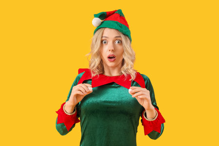 Shocked young woman dressed as elf on yellow backgroundの写真素材