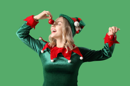 Funny young woman dressed as elf with apples on green backgroundの写真素材