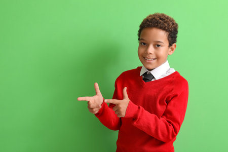 Little African-American boy showing gun gesture on green backgroundの写真素材