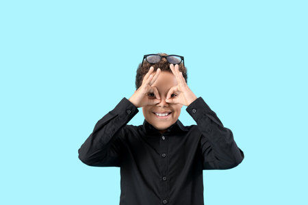 Funny little African-American boy showing OK on blue backgroundの写真素材