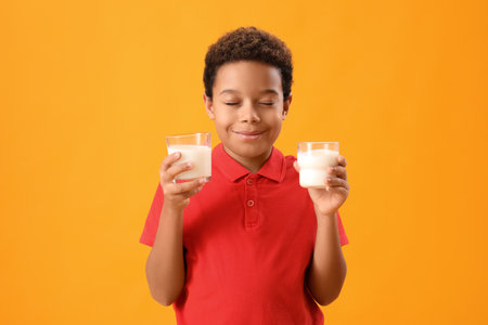 Dreaming African-American boy with glasses of milk on yellow backgroundの写真素材