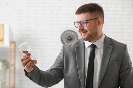 Young businessman with hourglass in office. Time management conceptの写真素材