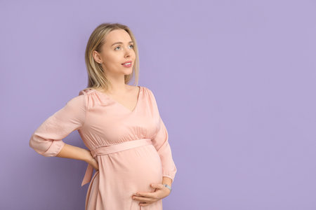 Happy pregnant woman on lilac backgroundの写真素材