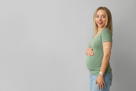 Young pregnant woman after vaccination on light backgroundの写真素材