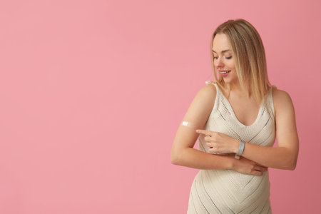 Young pregnant woman after vaccination on pink backgroundの写真素材