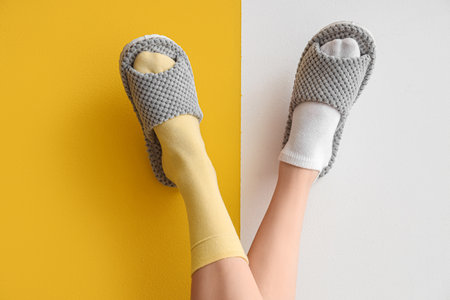 Female legs in soft slippers on yellow and white backgroundの写真素材