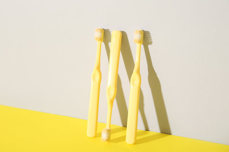 Three yellow toothbrushes on color background.の写真素材